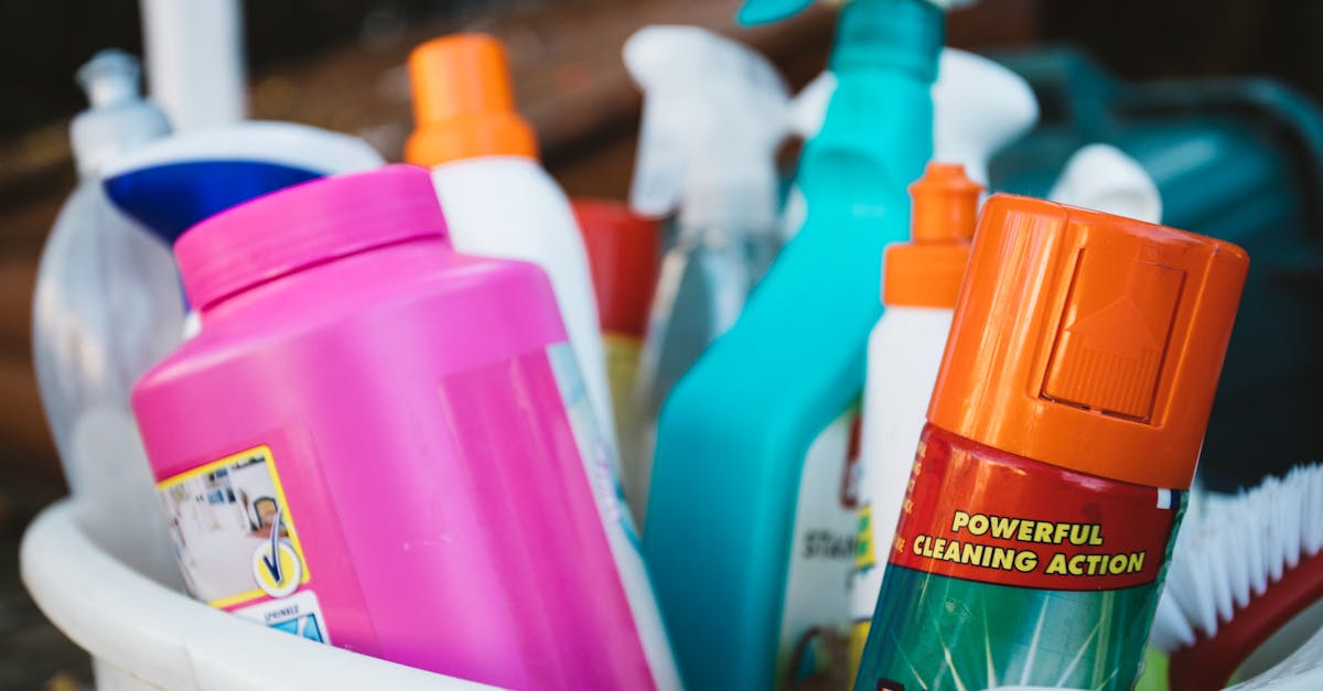 Close-up of assorted cleaning supplies in a bucket outdoors, showcasing various detergents and sprays.